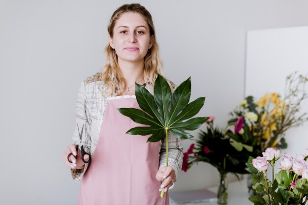 Foto gratuita floreria en delantal con hojas y tijeras