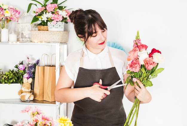 Foto gratuita floreria femenina cortando ramitas de flores con tijeras.