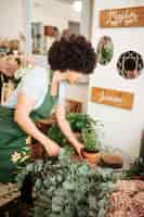 Foto gratuita floreria femenino que arregla la planta en conserva en tienda