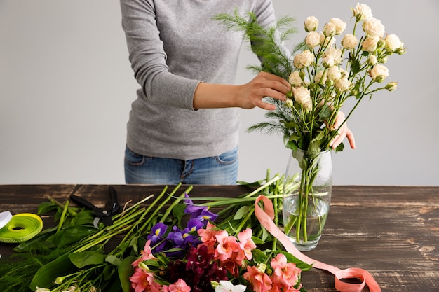 Floreria haciendo ramo de flores en florero