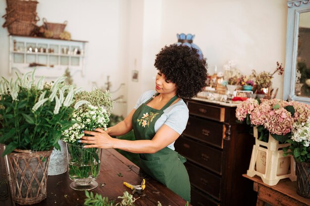 Floreria joven mujer africana arreglando flores en la tienda