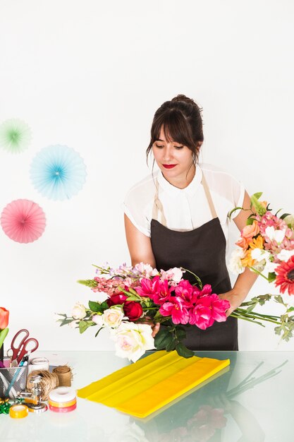 Floreria mujer colocando flores sobre tela amarilla