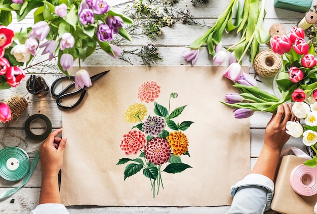 Floreria que muestra el diseño vacío Espacio que el papel en la mesa de madera con las flores frescas adorna