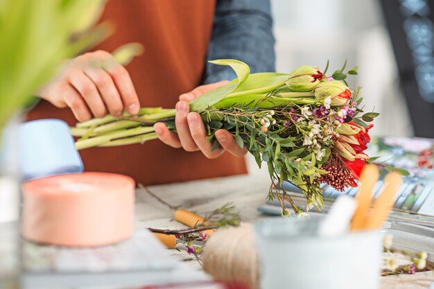 Floreria en el trabajo: las manos femeninas de la mujer haciendo moda moderno ramo de flores diferentes