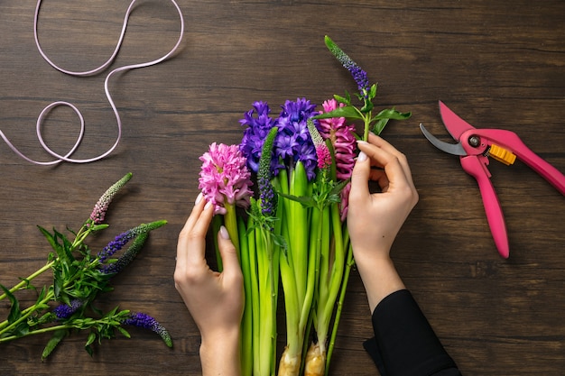 Floreria en el trabajo mujer haciendo moda ramo moderno de diferentes flores sobre fondo de madera