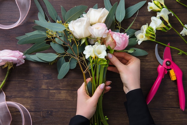 Floreria en el trabajo mujer haciendo moda ramo moderno de diferentes flores sobre superficie de madera