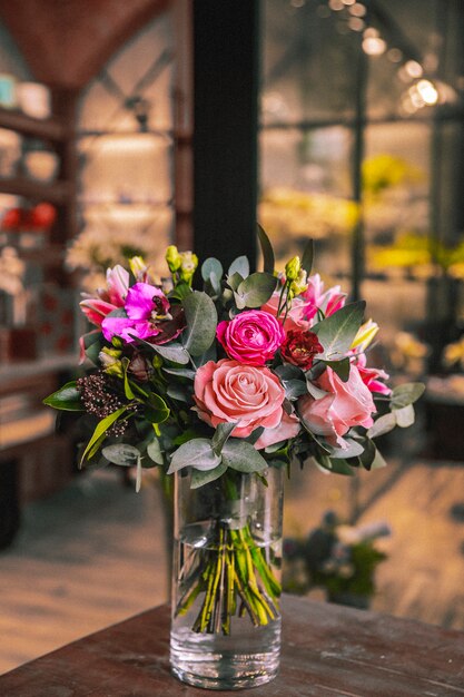 Florero con composición de flores en mesa de madera mezcla rosas