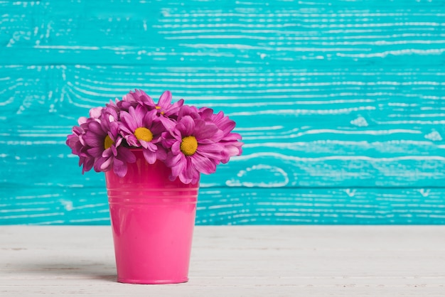 Florero con flores moradas y fondo de madera