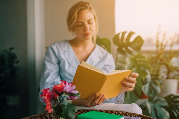 Florero en frente del libro de lectura joven hermosa mujer