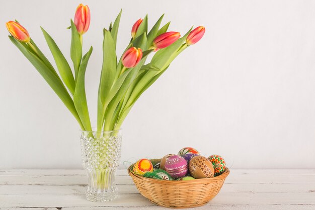 Florero con tulipanes cerca de huevos de Pascua