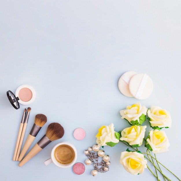 Flores amarillas con producto cosmético y taza de café sobre fondo blanco