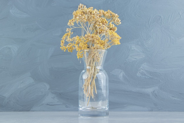 Flores amarillas secas en frasco de vidrio.