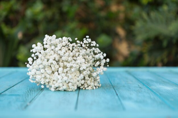 Flores blancas bonitas sobre mesa de madera azul