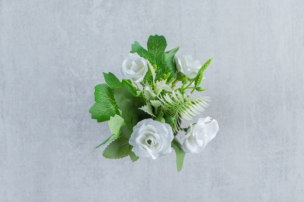 Flores blancas frescas en una jarra de madera, sobre la mesa blanca.
