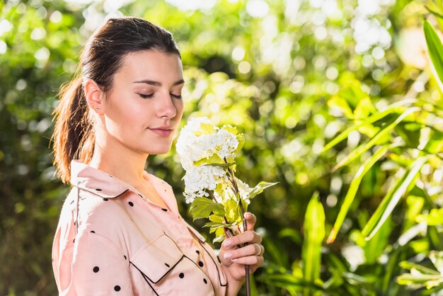 Flores blancas que huelen de la mujer bastante joven