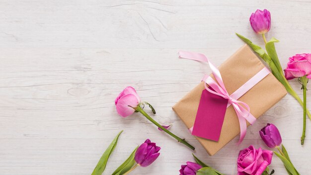 Flores con caja de regalo en mesa de luz.