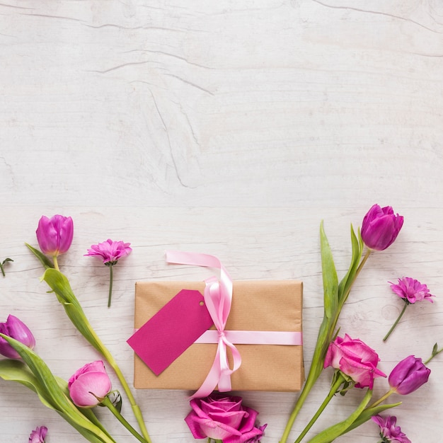 Flores con caja regalo en mesa madera.