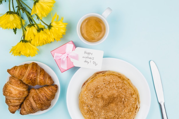 Foto gratuita flores cercanas al presente con etiqueta y platos con crepes y croissants.