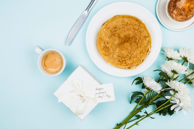 Flores cercanas al presente con etiqueta y platos con crepes.