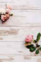 Foto gratuita flores de clavel y rosa en la mesa de madera vieja