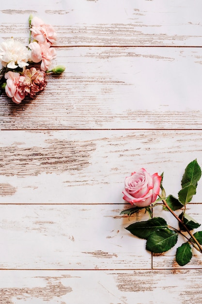 Flores de clavel y rosa en la mesa de madera vieja