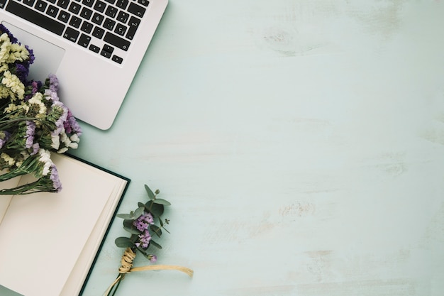 Foto gratuita flores y cuaderno cerca de la computadora portátil