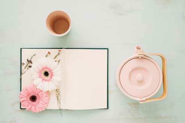 Foto gratuita flores y cuaderno cerca de taza y tetera