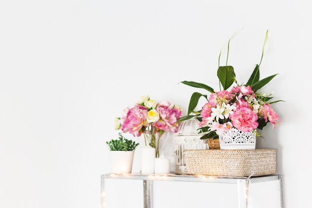 Flores decorativas en mueble frente a pared.