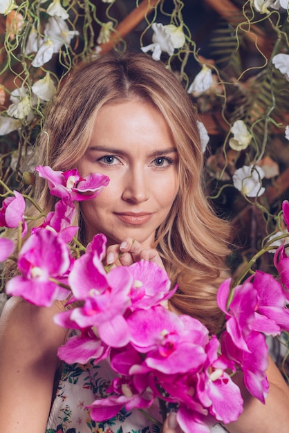 Flores exóticas de orquídeas frescas frente a una joven rubia