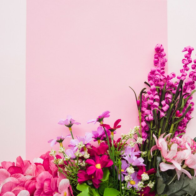 Flores falsas coloridas decorativas contra fondo rosado