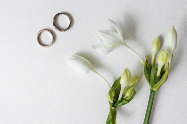 Flores florecientes con dos anillos de boda en el fondo blanco