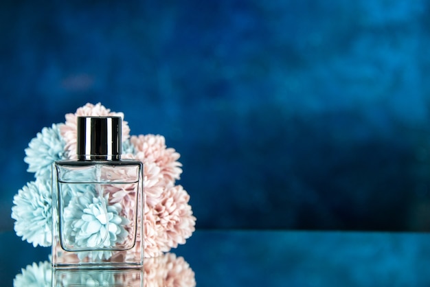 Flores de frasco de perfume de vista frontal sobre fondo azul oscuro con lugar libre