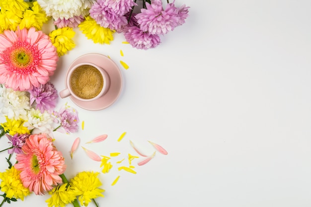 Foto gratuita flores frescas cerca de taza de bebida y pétalos