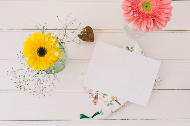 Flores de gerbera en jarrones con papel blanco.