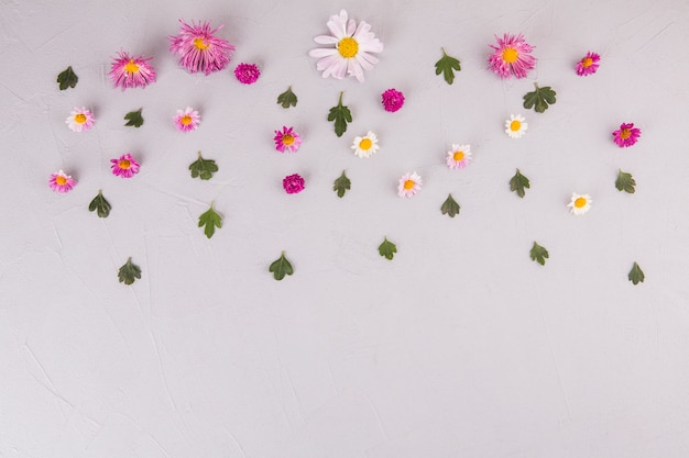 Flores con hojas verdes esparcidas sobre mesa de luz.