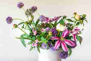 Foto gratuita flores de un jardín en un jarrón sobre un fondo blanco.