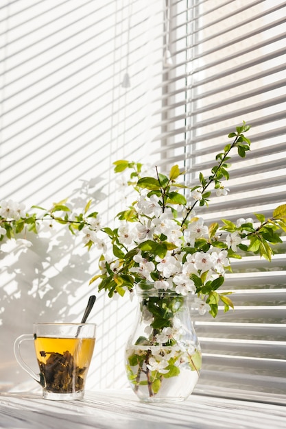 Flores en un jarrón con una taza de té