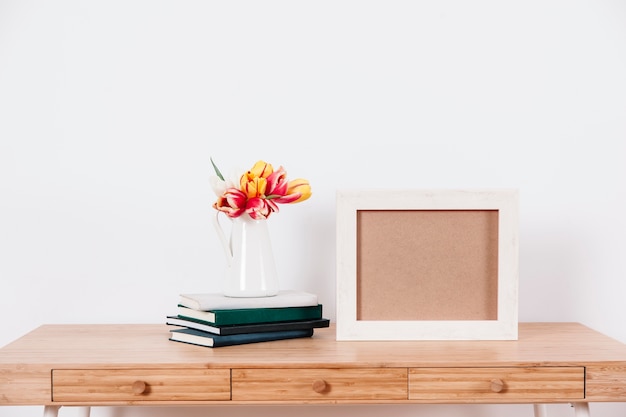 Flores y libros sobre la mesa cerca del marco