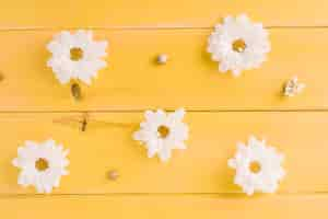 Foto gratuita flores de margarita blanca en tablón de madera amarilla