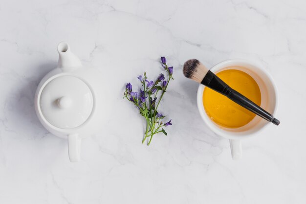 Flores y pincel cerca de una taza de té