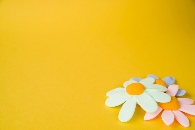 Flores planas de color pastel sobre fondo amarillo