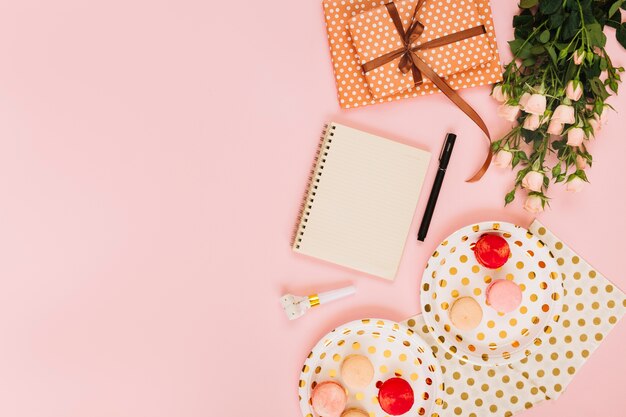 Flores y regalos cerca de cuaderno y macarrones