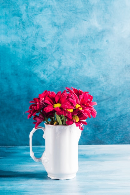 Flores rojas en jarra sobre mesa
