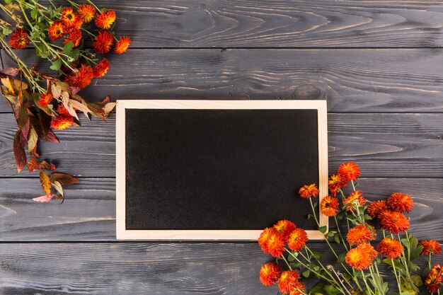 Flores rojas con pizarra en mesa de madera