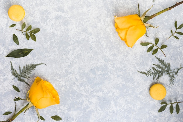 Foto gratuita flores de rosa con macarrones y ramas de plantas.