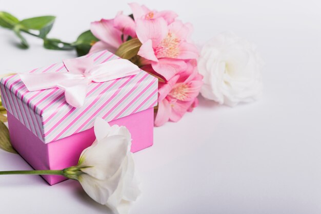 Flores rosadas y blancas con caja de regalo en el contexto blanco