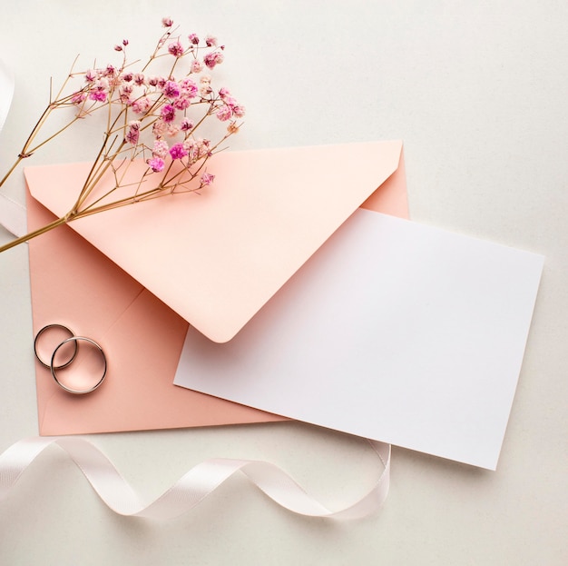 Las flores rosadas y el sobre guardan el concepto de la boda de la fecha