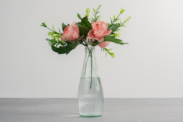 Foto gratuita flores rosas con hojas verdes en un jarrón de vidrio