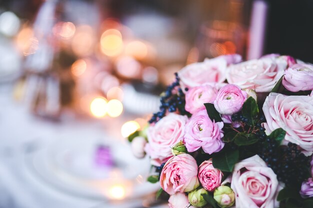 Flores rosas en un jarrón con una mesa desenfocada de fondo