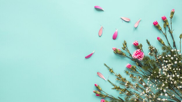 Flores rosas con ramas de plantas en mesa.